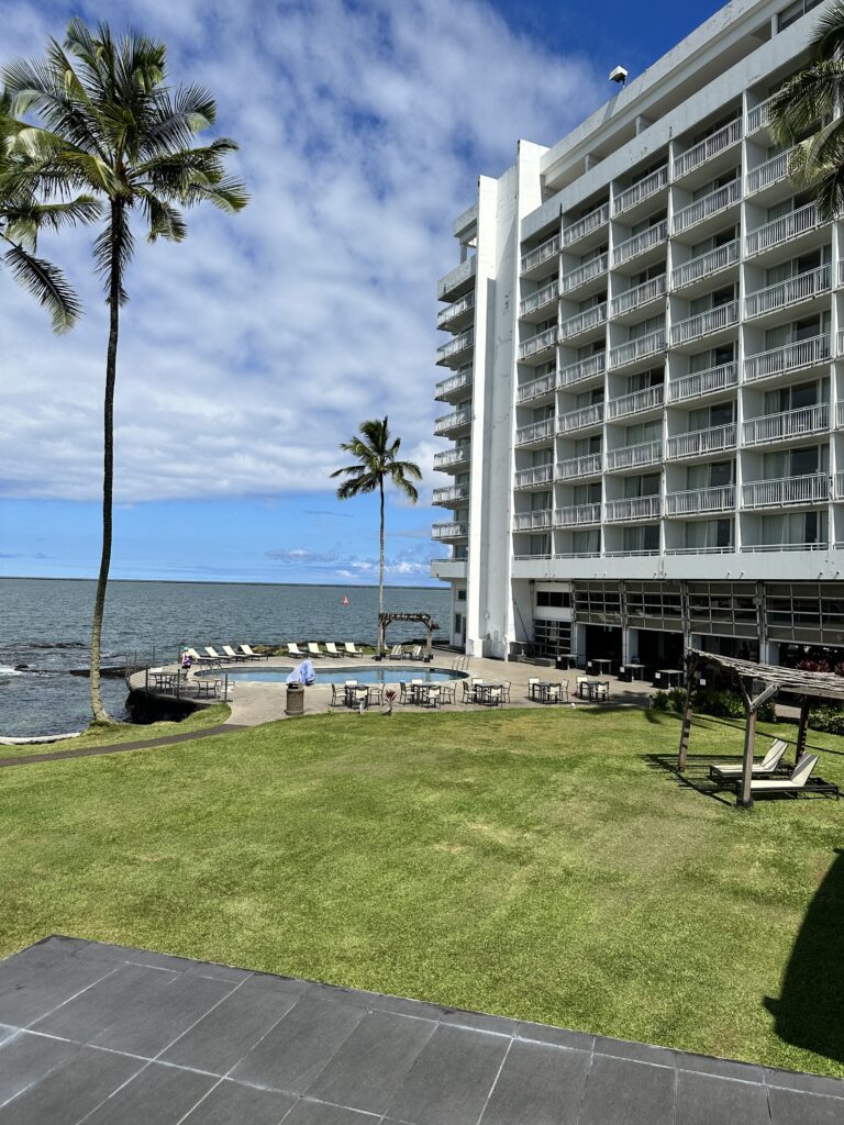 a large white building with a pool and palm trees