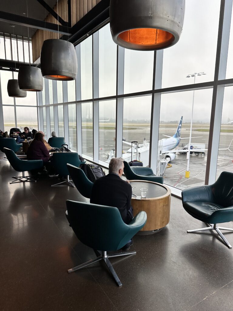 people sitting in chairs in a room with large windows