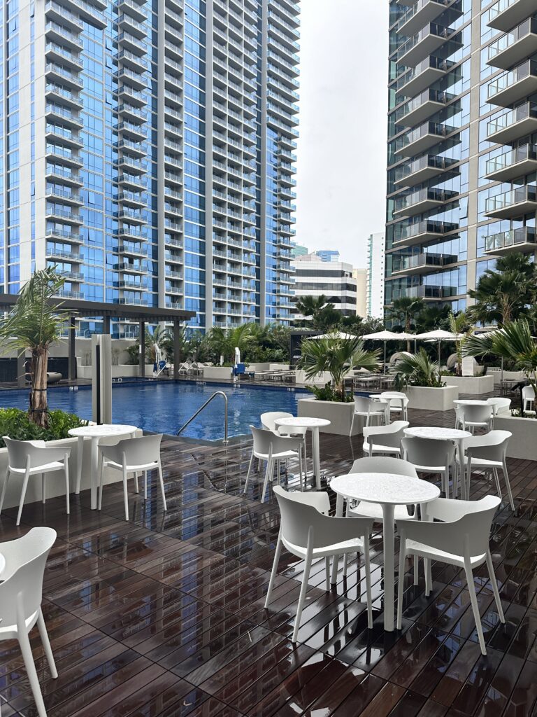 a pool with tables and chairs in front of a building