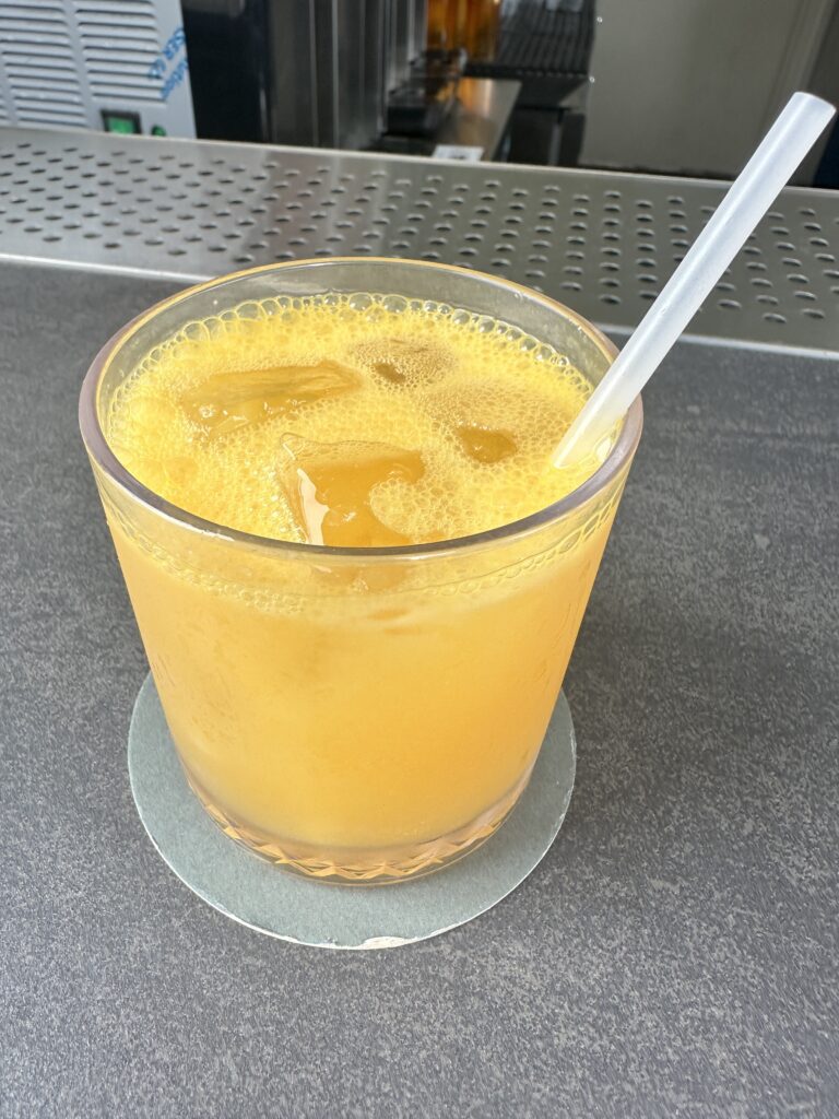 a glass of orange liquid with a straw