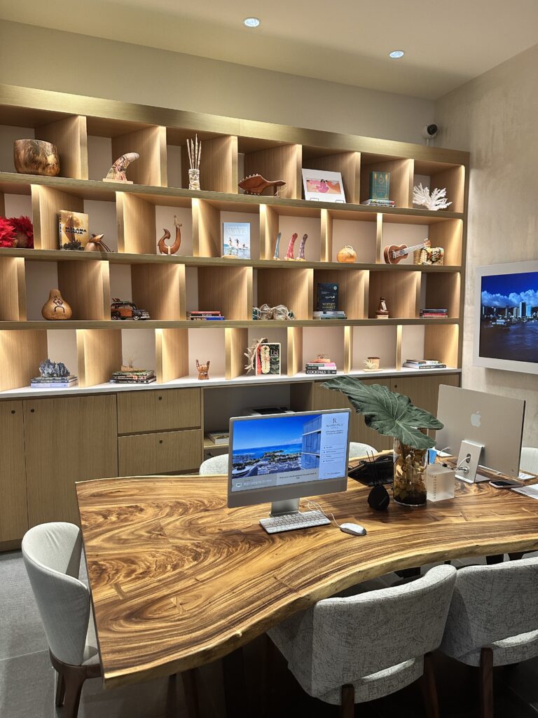 a desk with a computer and a shelf with pictures