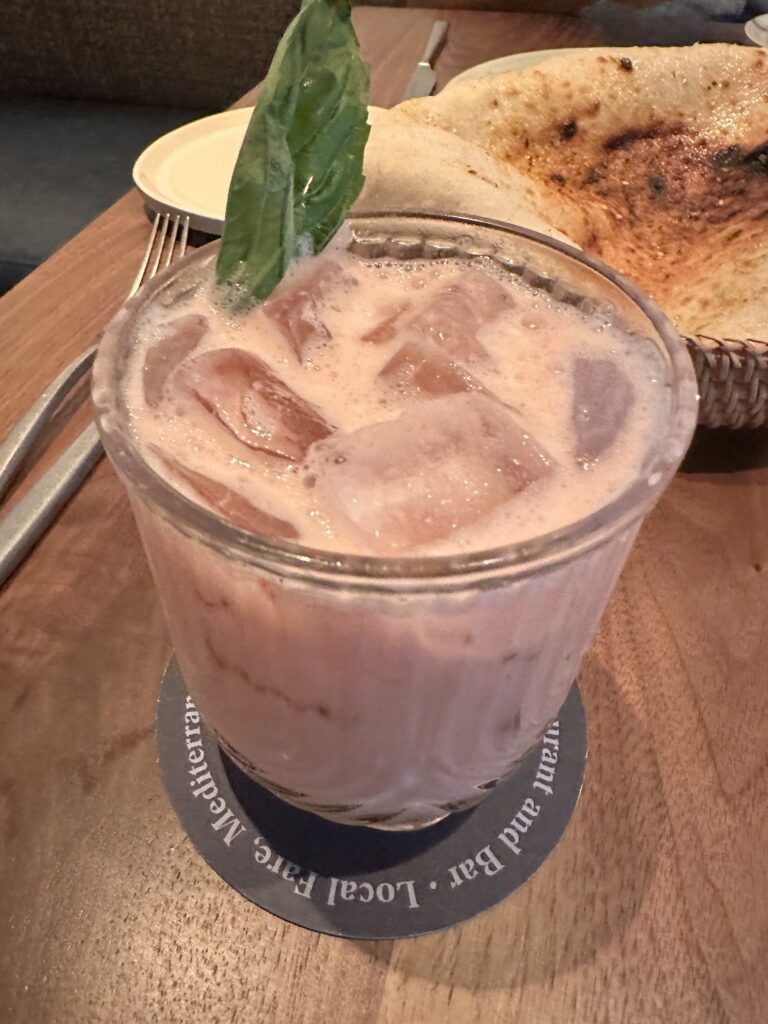 a glass of ice drink with ice cubes and a leaf on top