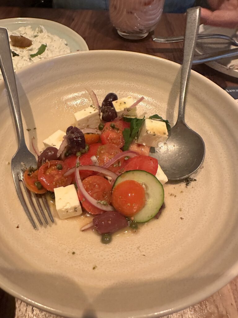 a plate of salad with fork and spoon