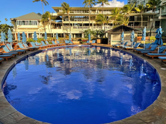 a pool with lounge chairs and umbrellas in front of a building