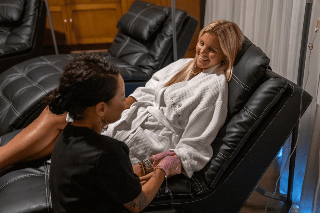 a woman sitting in a chair with a woman in a white robe