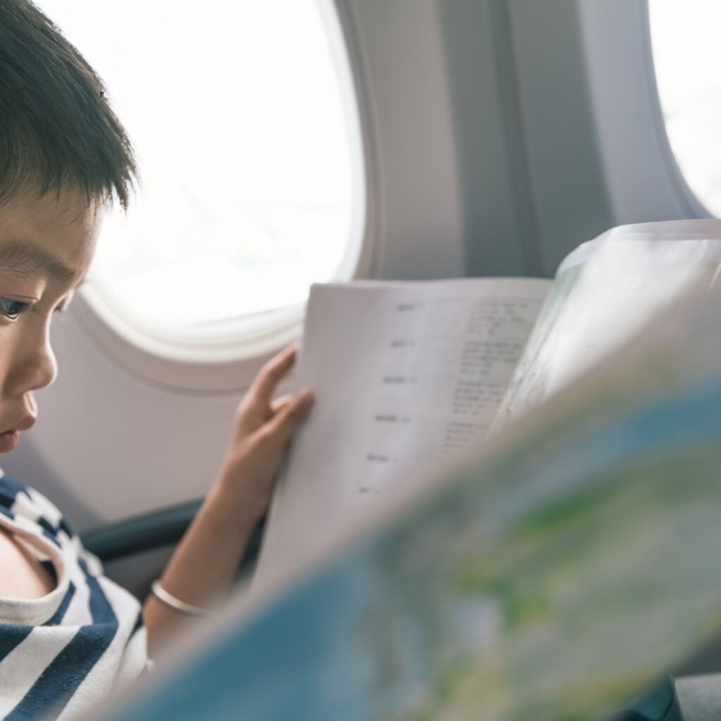 a boy reading a book on an airplane one of the best things to do on a long airplane flight