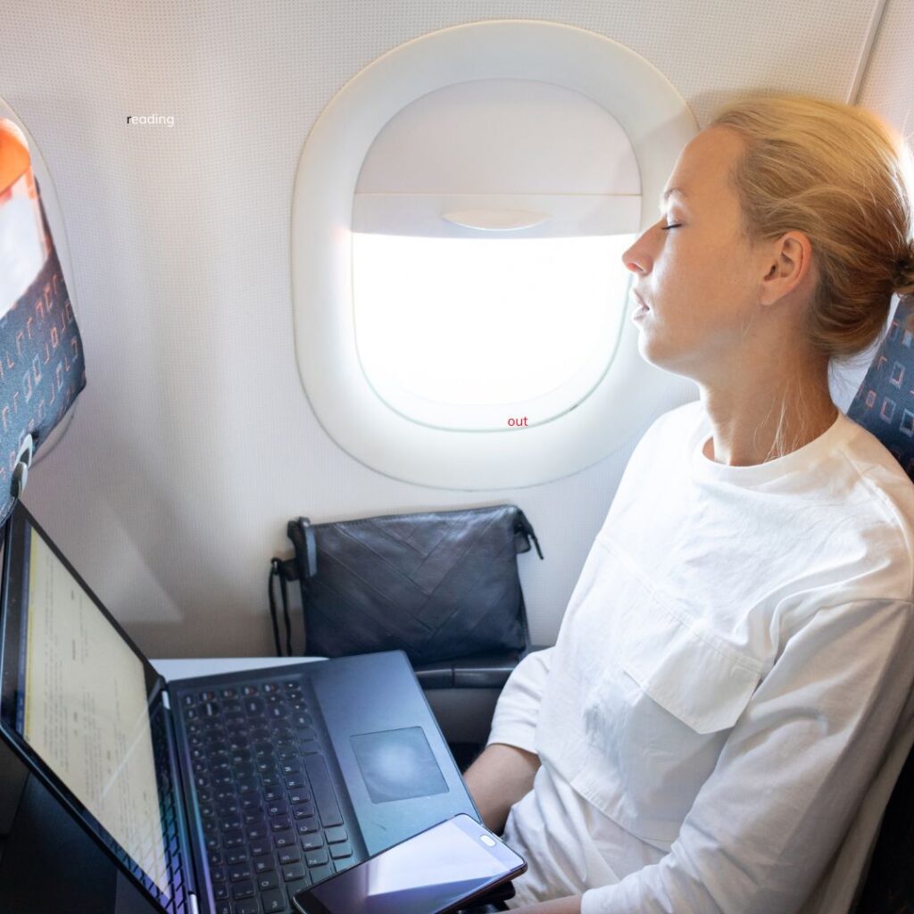 a woman sitting on a plane with a laptop