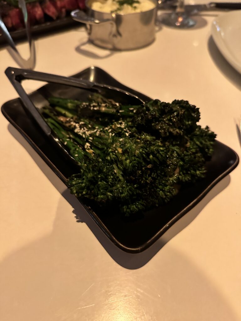 a plate of broccoli with tongs