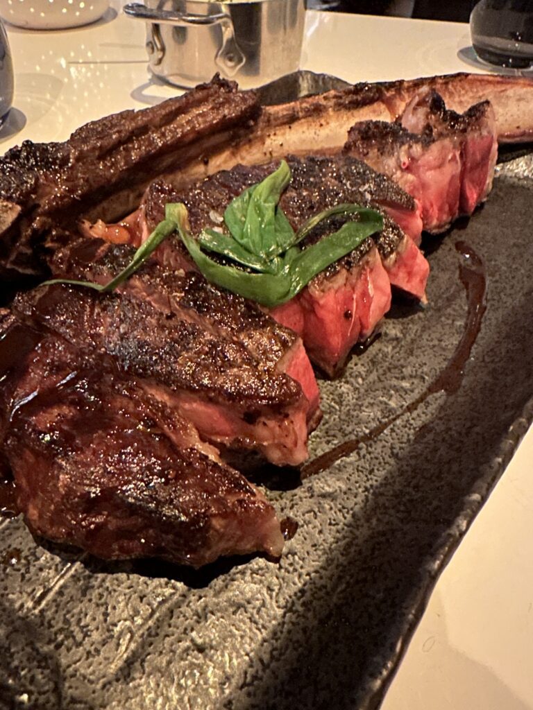 a plate of steak with a leaf on it