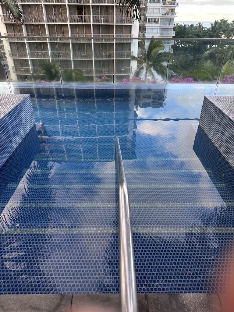 a pool with a railing and a building in the background