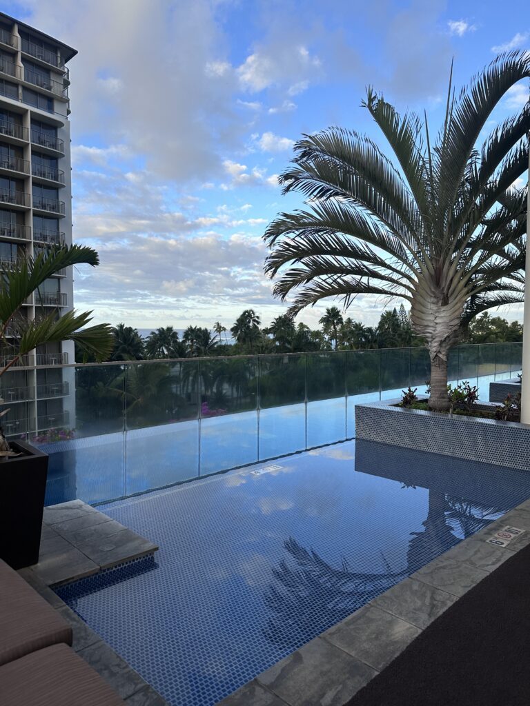 a pool with a palm tree and a building in the background