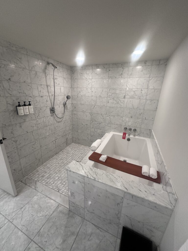 a white and marble bathroom with a bathtub and shower