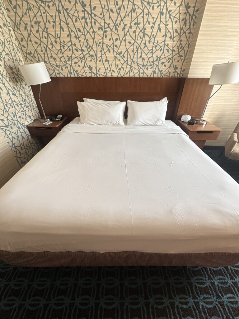 a bed with white sheets and lamps