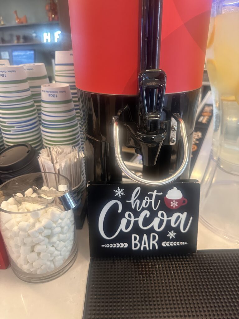 a hot cocoa bar with a sign and cups