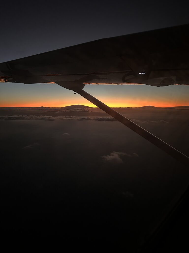 an airplane wing with the sun setting behind it