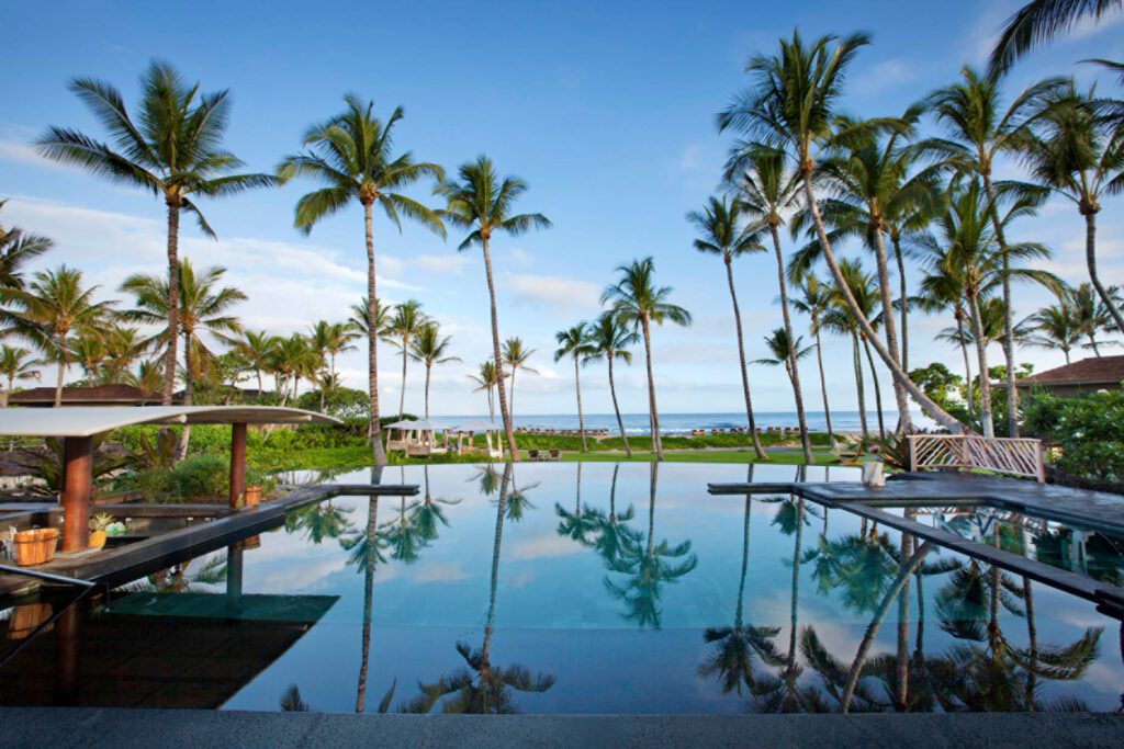 a pool with palm trees and a beach in the background