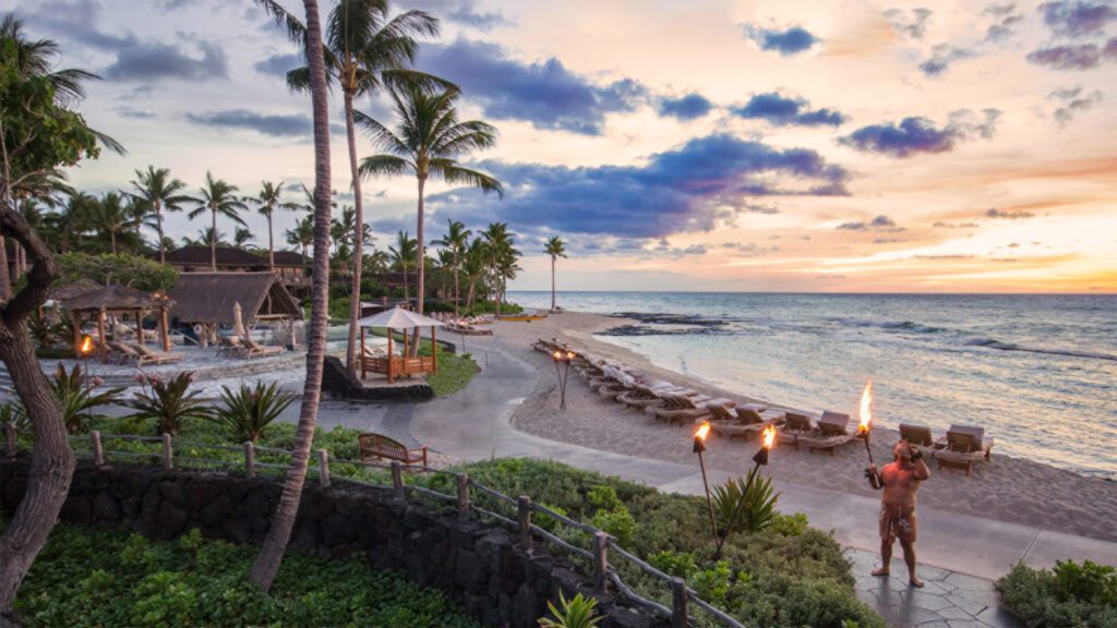 a beach with palm trees and chairs and a fire on the beach