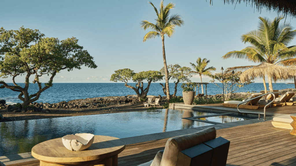 a pool with a deck and chairs on a beach